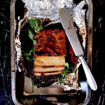 top view of sliced marinated tofu in tin foil with coriander and a sharp knife