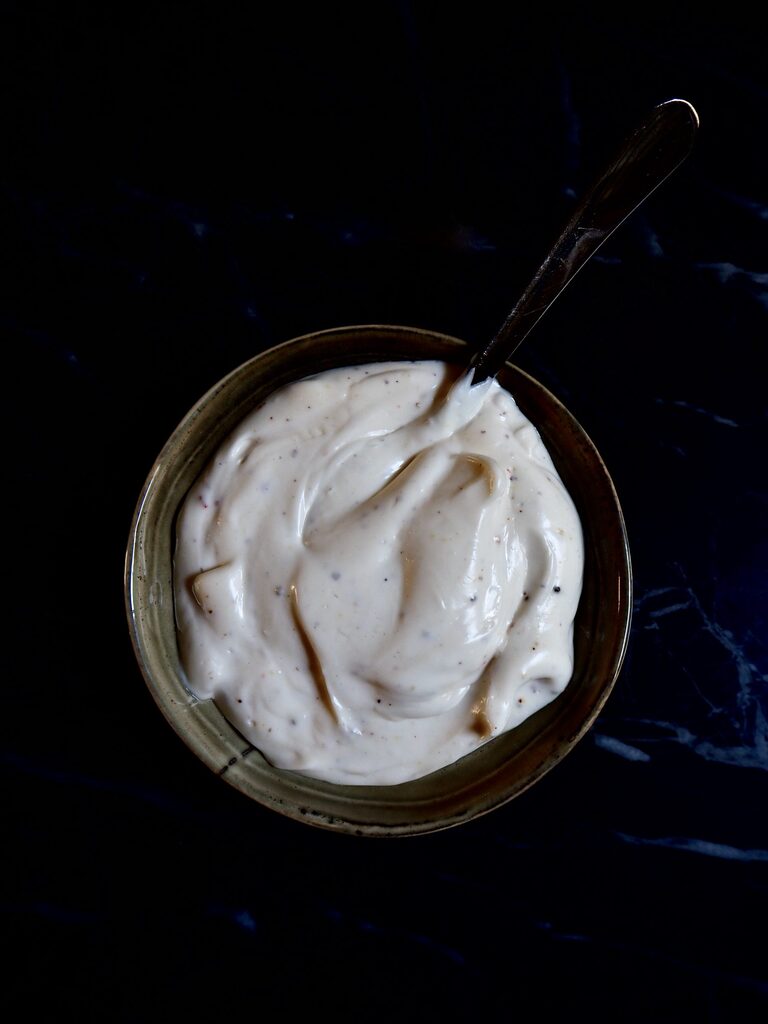 easy vegan aioli seen from above in a small bowl with a silver spoon against a dark backdrop