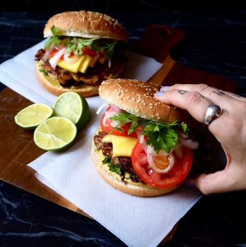 dos hamburguesas con mango con una mano cogiendo la de derecha.