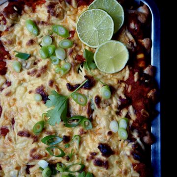 enchiladas with roasted vegetables seen from above topped with coriander, spring onion and lime.