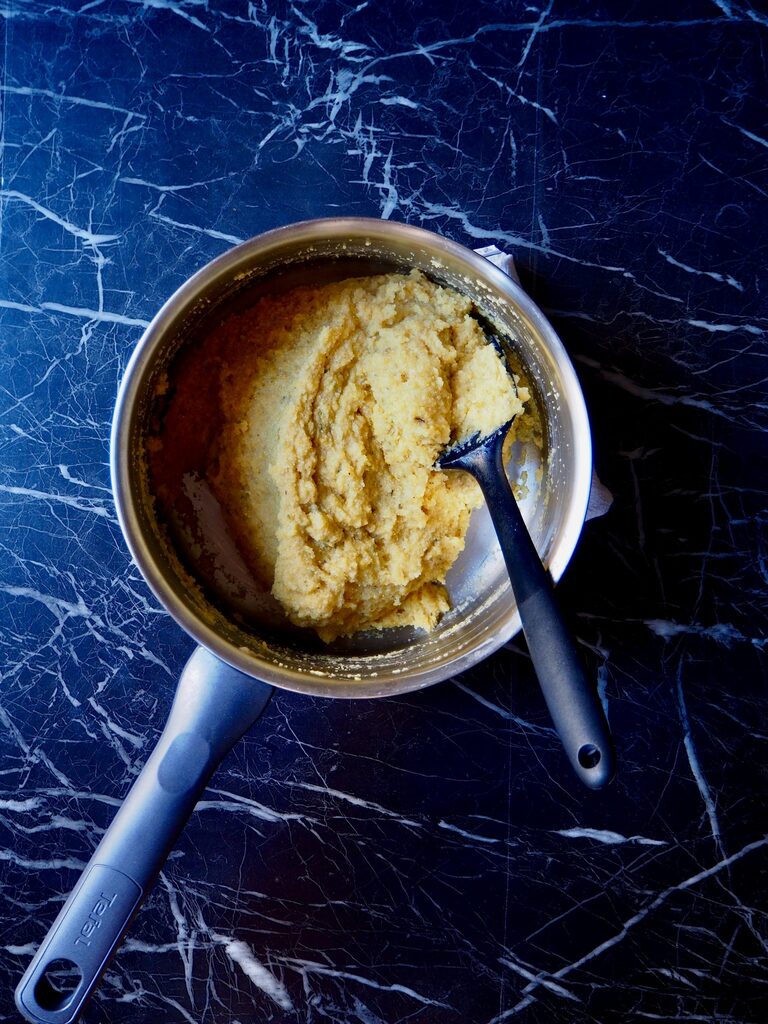 cooked polenta seen from above in a pot with a black spatula