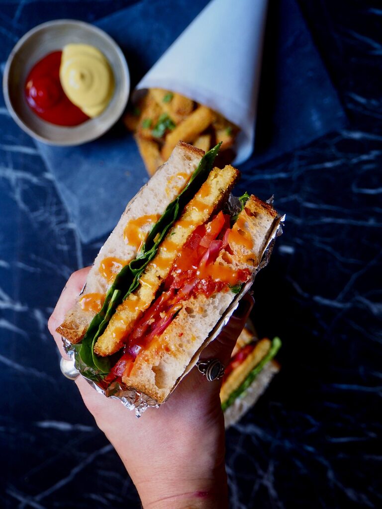 een close up van de polenta sandwich met de frietjes op de achtergrond