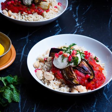 vegan borani banjan seen up close front view, two white bowls, a twig of mind, a little brown bowl with lemons to the side