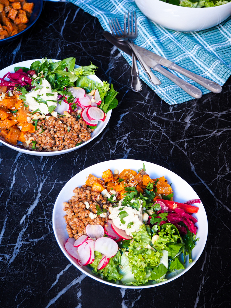 two spiced lentil and sweet potato bowls seen from a front view with some cutlery in the background