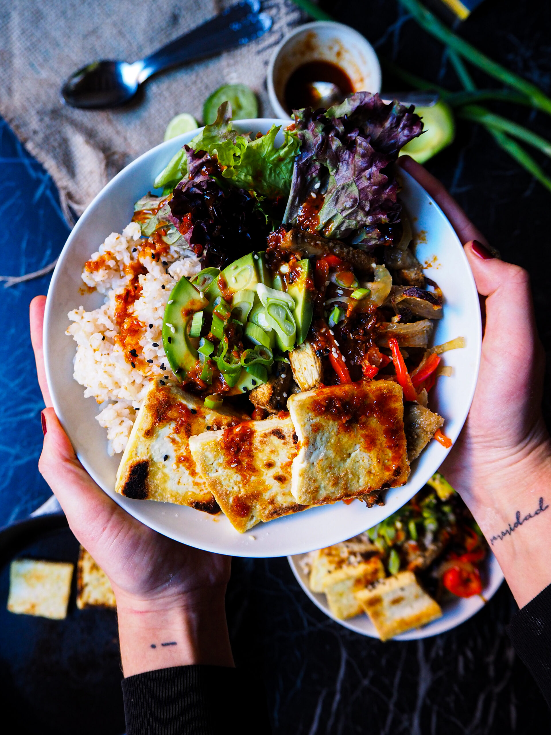 a tofu bowl with sesame vinaigrette seen up close help up by two of my hands