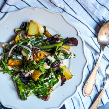 vegan sicilian bean salad on white plate with silver fork and knife to the right side photographed from above