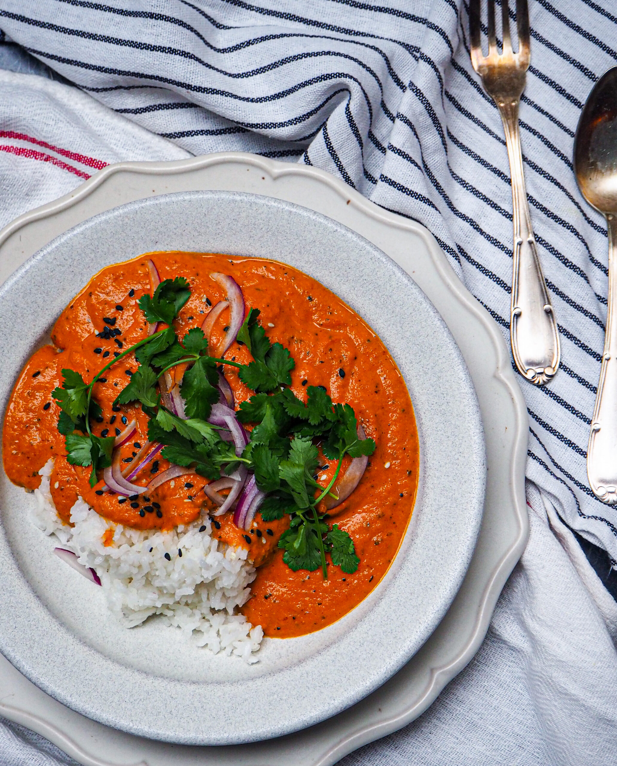 vegan butter chicken curry seen from above against a white back drop with silver vintage cutlery